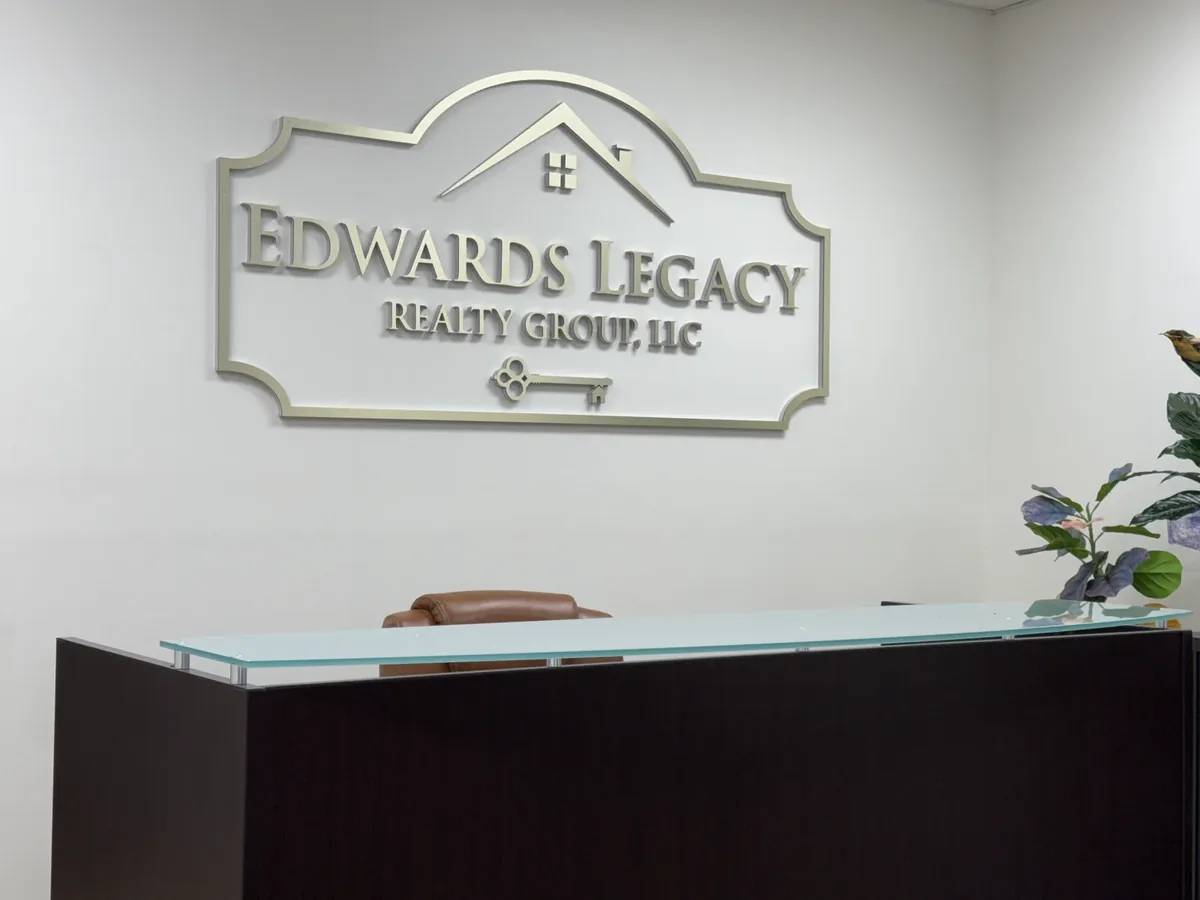One of our custom indoor signs in Mobile: the Edwards Legacy Realty Group dimensional lobby sign, a silver frame with a house roofline and a key, on the wall above a reception desk