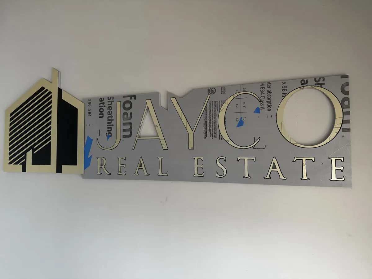 Jayco Real Estate dimensional logo going up on an office wall, its foam mounting template still around the letters