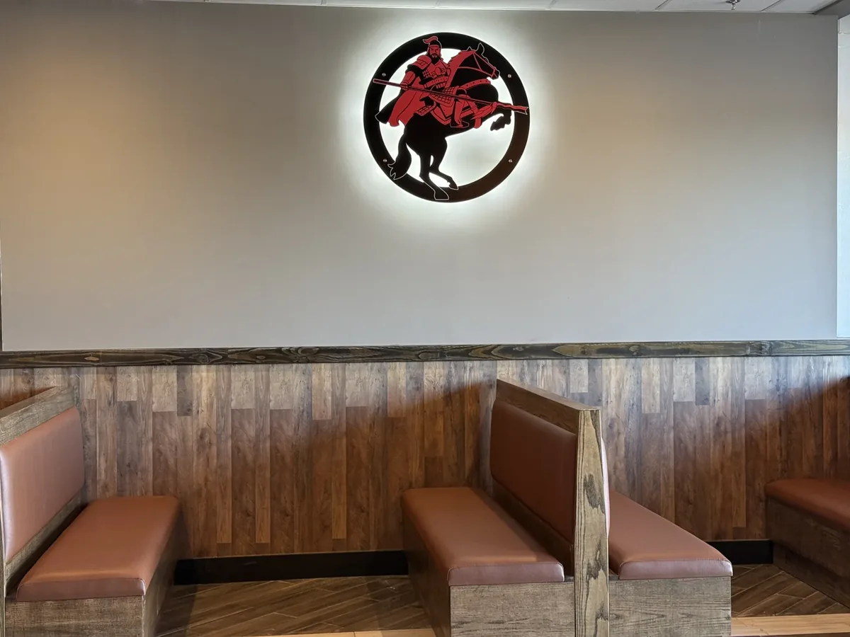 Komo Yaki round knight logo glowing with a white halo on the wall above restaurant booths